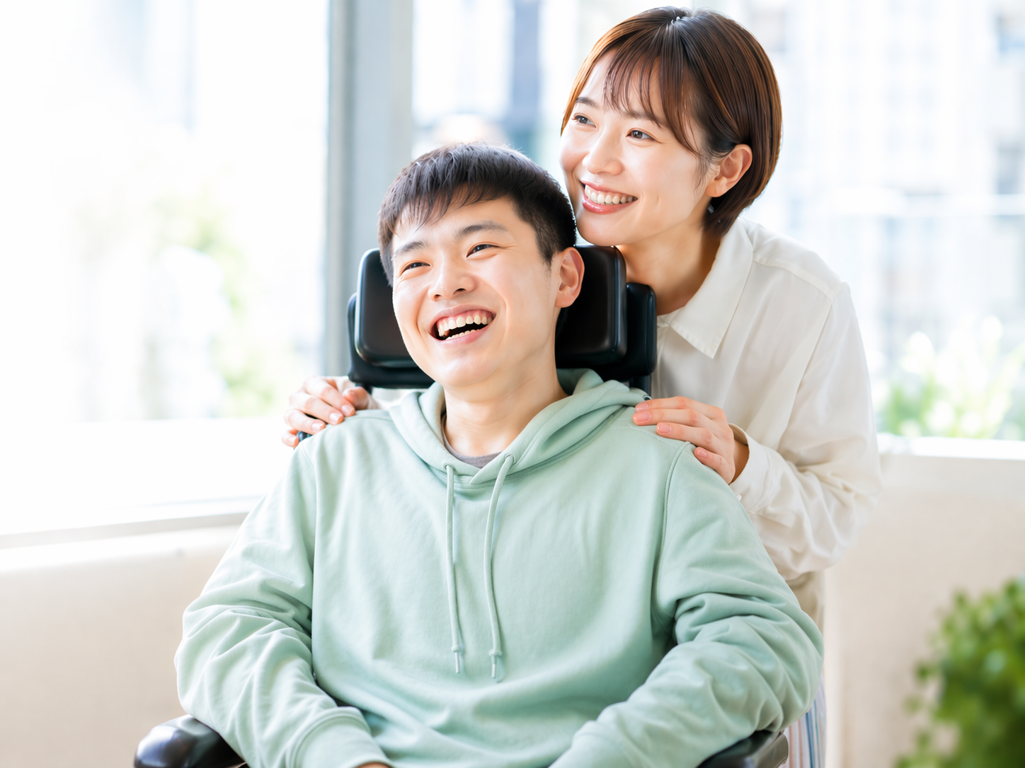 車椅子の男性とそれを支える女性の笑顔